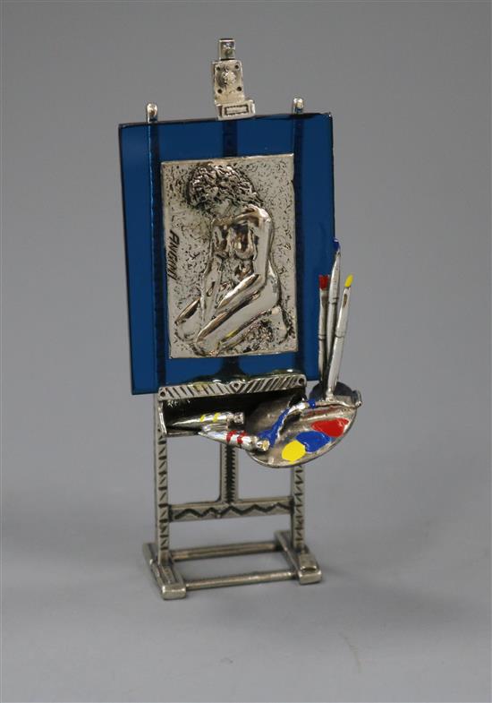 An Italian post 1968 800 white metal, enamel and glass model of an easel, with pallet and portrait, 10.3cm.